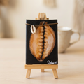Tiny cowrie shell artwork on a miniature easel